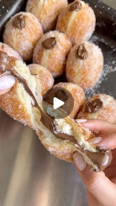 a person holding a donut with chocolate on it