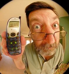 a man with glasses holding up a cell phone in front of his face and looking at the camera