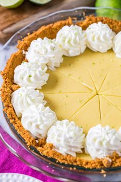 a pie with whipped cream and limes on the side sitting on a glass platter