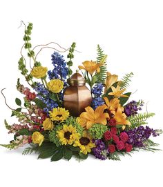 a vase filled with lots of colorful flowers and greenery next to a candle holder