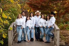 a group of people standing on a wooden bridge in front of trees and bushes, posing for a photo