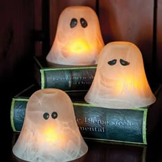 three lighted ghost candles sitting on top of books