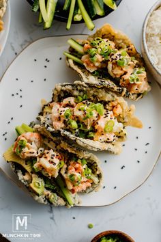 an assortment of sushi on a plate next to rice and broccoli in bowls