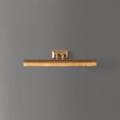 a wooden shelf with a gold handle on it against a gray wall in an apartment