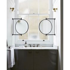 two round mirrors are hanging above the sink in this bathroom with white walls and black cabinetry