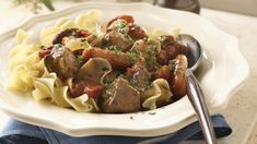 a white plate topped with pasta and meat covered in sauce on top of a blue napkin