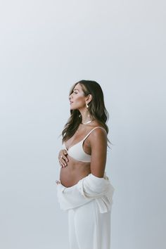 a woman in white is standing with her hands on her hips and looking off to the side