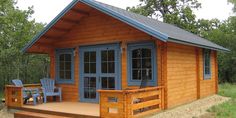 a small wooden cabin with blue windows and steps leading up to the front porch area