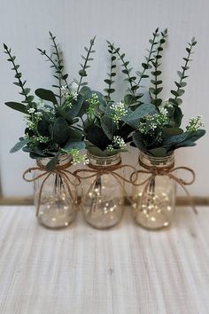 four glass vases with plants in them on a table