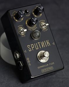 a black and gold pedal box sitting on top of a white plate with knobs