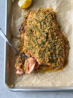 a pan filled with meat covered in seasoning next to lemon wedges and a knife