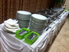 the table is set with plates, silverware and green trays on it's sides