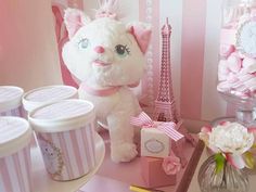 a stuffed cat sitting on top of a table next to cupcakes and other items