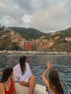 three women sitting on the back of a boat waving to someone in front of them