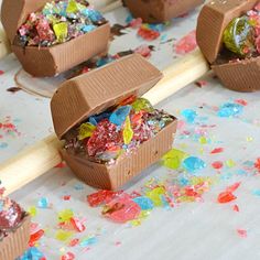 there are many pieces of cake in the box on top of a stick and sprinkles all around it