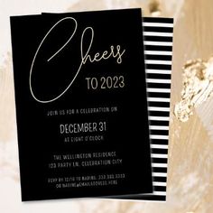 a black and white striped party card with gold foil lettering on the front, featuring cheers to 2012