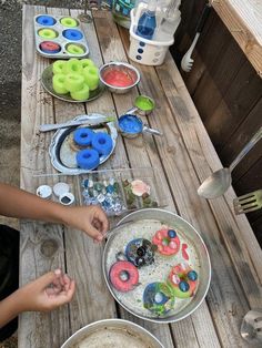 two children are making doughnuts on a picnic table with bowls and utensils