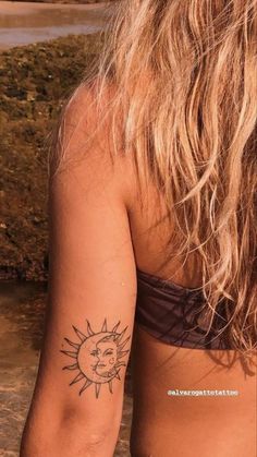 a woman with a sun tattoo on her left arm and chest, standing in the water