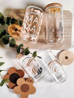 two mason jars sitting on top of a wooden cutting board next to flowers and leaves