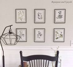 a wooden chair sitting in front of a table with pictures on the wall behind it