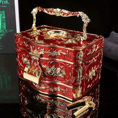 a red and gold decorated box sitting on top of a black table next to a mirror