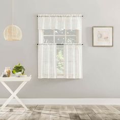 a white table sitting in front of a window next to a wall with pictures on it