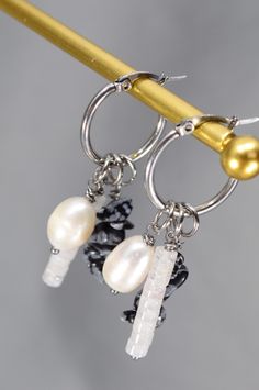 Discover the perfect blend of sophistication and boldness with these unique pin hoop earrings from Estibela. Handcrafted from durable stainless steel, these earrings feature a lustrous freshwater baroque pearl bead, a vibrant quartz bead, and a natural stone bead with an irregular shape. Designed in a boho style with subtle ethnic and vintage influences, they’re ideal for creating relaxed, expressive looks. Perfect for everyday wear, summer outings, or casual gatherings, they pair beautifully with light dresses, sundresses, and casual outfits. 
#BohoEarrings #HandcraftedJewelry #UniqueDesign #FreshwaterPearl #QuartzBead #EthnicStyle #VintageInspired #StatementJewelry #HandmadeAccessories #JewelryGift #BohoChic #FashionJewelry #EcoFriendly #ArtisanJewelry Handmade Pearl Dangle Hoop Earrings, Handmade Small Hoop Pearl Earrings, Metal Dangle Hoop Earrings With Pearl Charm, Pearl Charm Dangle Hoop Earrings, Bohemian Dangle Earrings With Pearl Charm, Light Dresses, Dresses Sundresses, Casual Festival, Ethnic Earrings