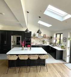 a large kitchen with an island in the center and skylights above it, along with wicker bar stools