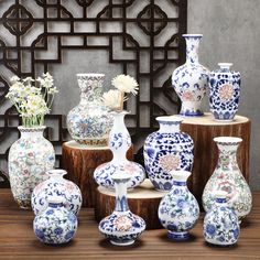 many different vases and flowers on display in front of a decorative paneled wall