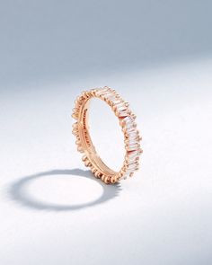 a rose gold ring with white stones on the inside and outside, set against a plain background