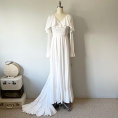 a white dress is on display next to a suitcase