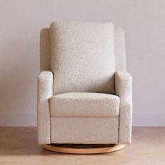 a white rocking chair sitting on top of a hard wood floor next to a wall