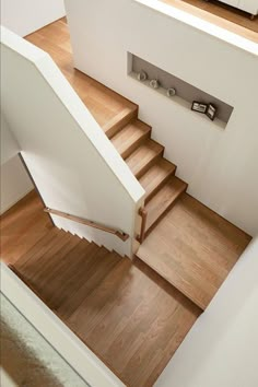 an overhead view of a stair case with wood floors and handrails in the foreground