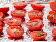 sliced tomatoes on tin foil with seasoning sprinkled on them, ready to go into the oven