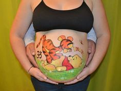 a pregnant woman holding her belly with winnie the pooh on it's side