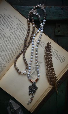 This transformative and empowering Japa Mala was inspired by Kundalini -  a spiritual and yogic concept that has been around for centuries. Made with Moonstone, Dendritic Opal, Quartz and Herkimer Diamonds this mala is finished with a silver tone serpent - symbol of the force, residing at the base of your spine. The spirit of a Serpent can be thought of as a rebirth, a transformation, and healing of the old form (be that mind, body, and spirit) as it sheds it's skin and regenerates a new being. Kundalini energy therefore is said to be like a snake, coiled at the base of the spine waiting to be released to your highest power. Symbolically this energy also moves like a serpent and is awakened by specific meditation and consciousness techniques. Circumferential length of this mala is about 42 Spiritual Hand Knotted Beaded Necklaces For Festivals, Spiritual Hand Knotted Beaded Necklace For Festivals, Holistic Hand Knotted Jewelry For Rituals, Bohemian Hand Knotted Necklace For Rituals, White Hand Knotted Spiritual Jewelry, Artisan Hand-knotted Beaded Necklaces For Meditation, White Bohemian Hand Knotted Necklace, White Hand Knotted Bohemian Necklace, White Bohemian Hand-knotted Necklace