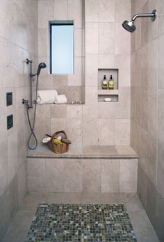 a bathroom with tiled walls and flooring, shower head, and bathtub in the corner