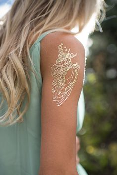 a woman with gold tattoos on her arm