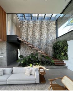 a living room filled with furniture next to a stone wall covered in plants and greenery