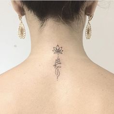 the back of a woman's neck with a small flower tattoo on her left side