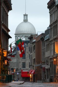 a city street with buildings and flags flying in the wind