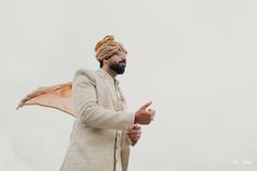 a man wearing a turban and standing with his hand out to the side