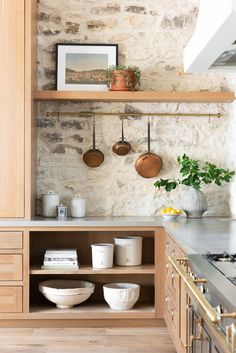 an open cabinet with pots and pans on the shelves next to a kitchen counter