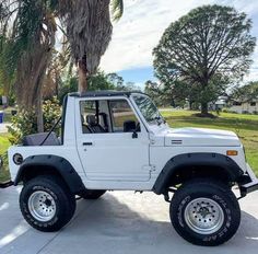 a white jeep is parked in front of a palm tree on the side of the road