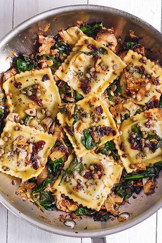 a pan filled with pasta and spinach covered in cheese, sauce and seasoning