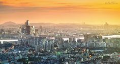 an aerial view of a city at sunset with mountains in the background