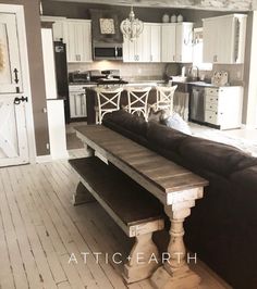 a living room and kitchen area with white cabinets, black couches and wooden flooring