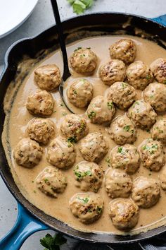 a skillet filled with meatballs covered in gravy and garnished with parsley