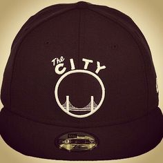 the city snap back hat is black with white embroidery on the front, and has a golden gate bridge in the background