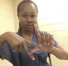 a woman with dreadlocks making the peace sign while standing in front of a mirror